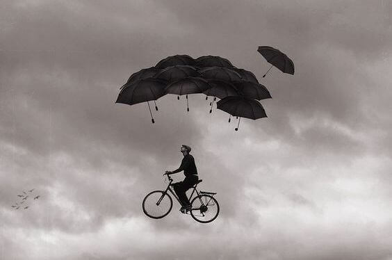 Mann sykler i luften under paraplyer