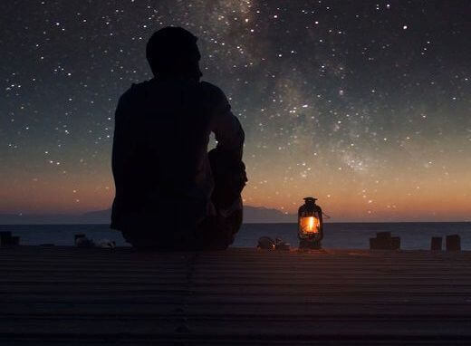 Mann på brygge ser på stjernene