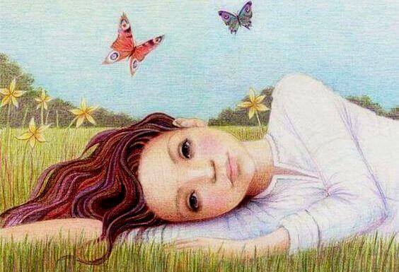 jente ligger i gresset ved sommerfugler