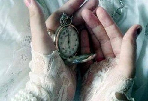 Hender holder et gammelt ur