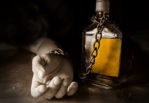Hånd lenket til flaske med alkohol