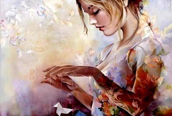 Jente holder origamifigurer i tråder