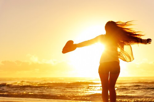 Lykkelig kvinne på stranden i solnedgangen