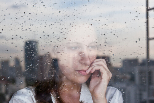 Kvinne ser ut regnfullt vindu