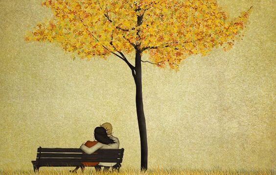 Par på en benk under et tre