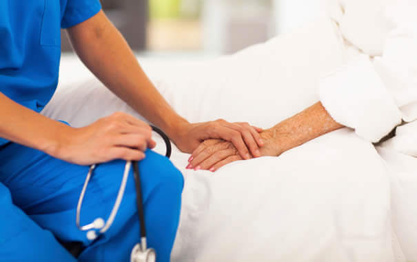 Sykepleier holder pasientens hånd