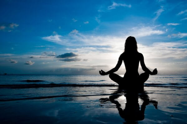 Kvinne mediterer ved havet