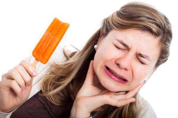 En kvinne med tannsmerter fra å spise saftis