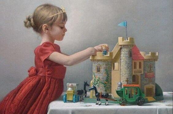 En liten jente bærer en tiara og leker med et slott