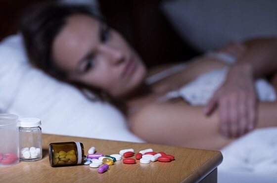 En kvinne ser på medisinering på nattbordet
