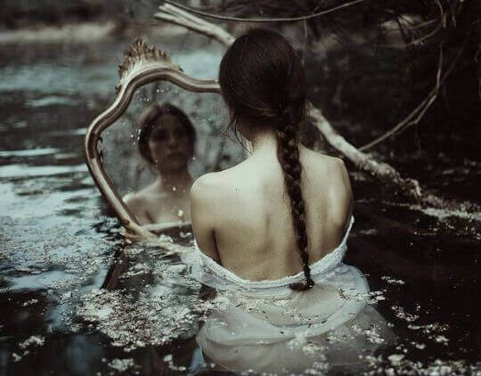 Kvinne i vann ser i speil