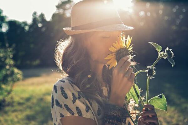 Kvinne lukter på blomst og praktiserer positiv tenkning