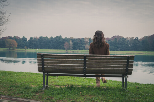Kvinne sitter på en benk i parken og dveler ved fremtiden