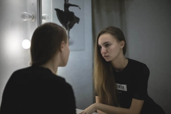 En trist kvinne ser i speilet
