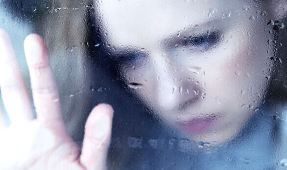 Trist kvinne bak vått glass