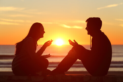 Vit hvordan du skal uttrykke deg selv: Par sitter på stranden ved solnedgang
