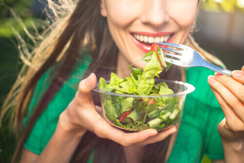 Smilende kvinne holder salatbolle