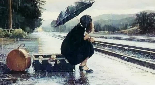 Kvinne sitter på koffert under paraply