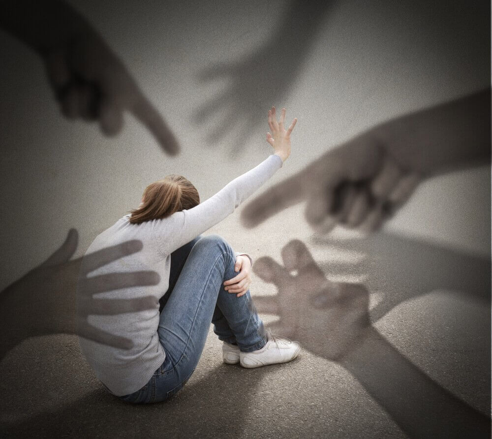 Mange gigantiske hender peker på en jente på bakken.