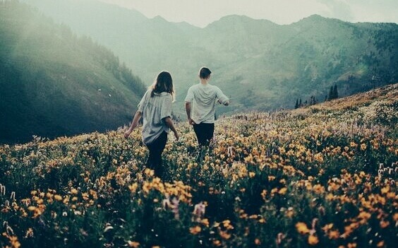 Two people walking in a mountain filled with flowers