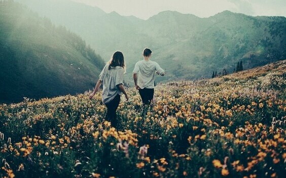 To personer som vandrer i et fjell fylt med blomster