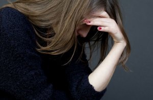 Dame som sitter med hodet i handa