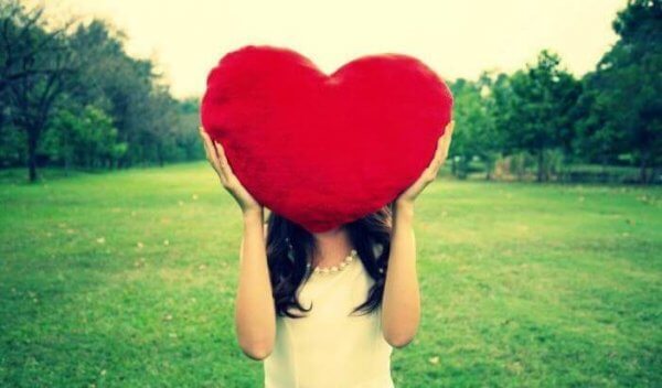 En kvinne som holder et stort, rødt hjerte over hodet sitt