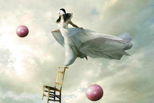 Kvinne balanserer på en stol med rosa baller i luften