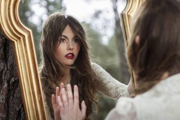 en kvinne ser på arrene sine i et speil
