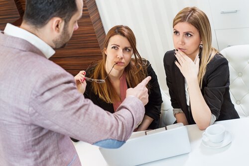 Mannlig sjef diskuterer med to kvinnelige ansatte