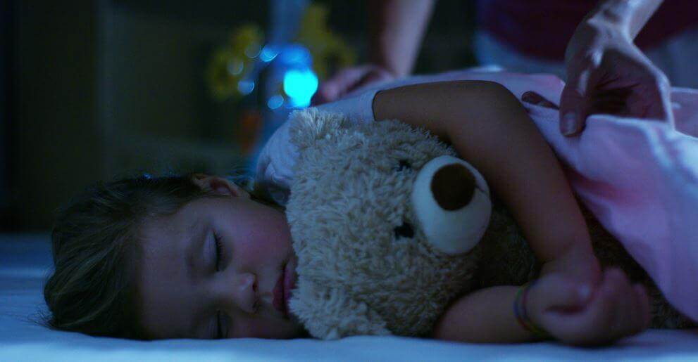 En liten jente som sover med kosebamsen sin