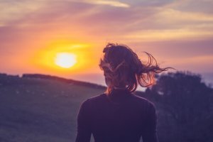 En dame som står å ser på solen