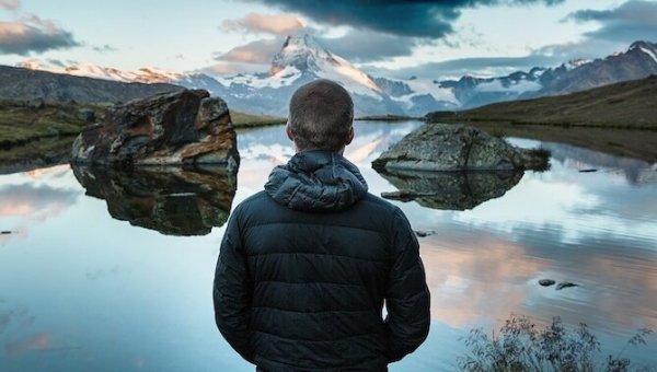 En mann som ser på en sjø, reflekterer og overveier.
