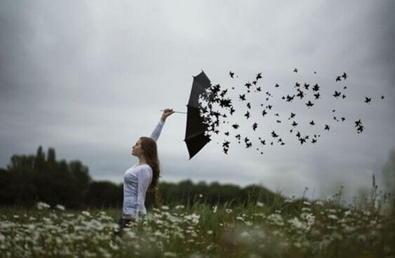 En kvinne med en paraply som forvandler seg til fugler.