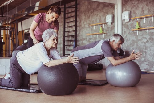 Eldre mennesker trener på yogaballer med trener.