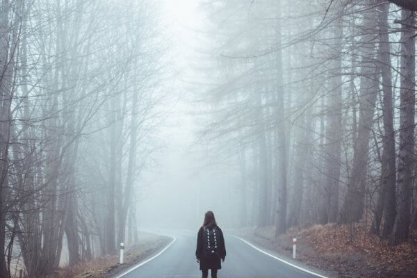 Kvinne går langs grå vei