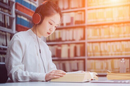 Kvinne lytter til musikk og leser