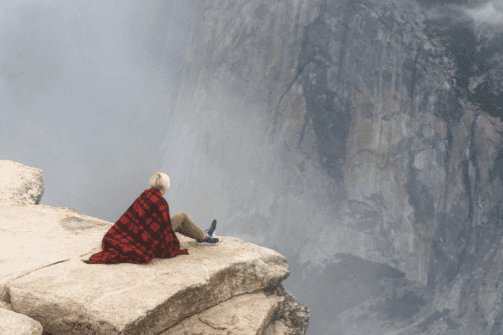 Kvinne sitter på klippekant