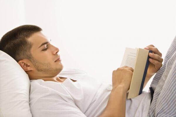 Mann leser i sengen