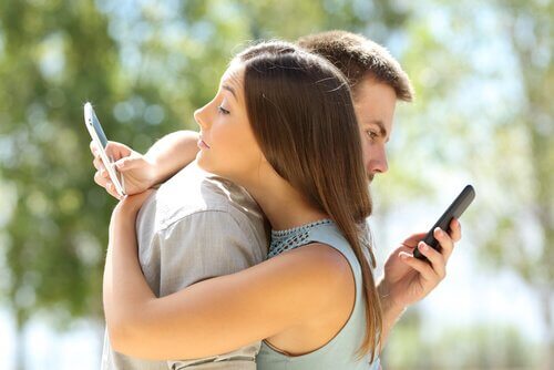 Par klemmer hverandre mens de bruker telefonene sine