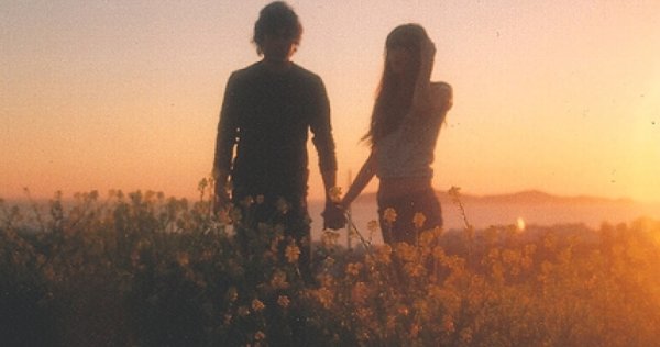 Par holder hender i solnedgang