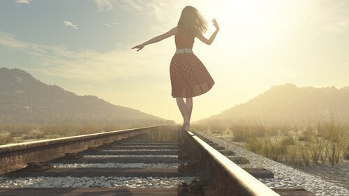 Kvinne går på jernbanespor
