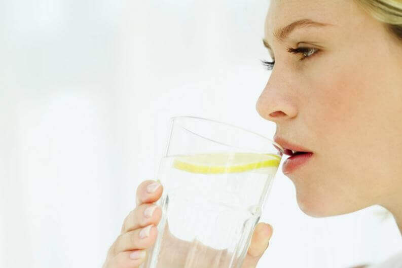 Kvinne drikker varmt vann med sitron