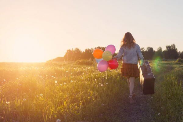 Jente med koffert og ballonger