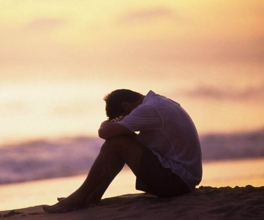 Mann sitter ved havet