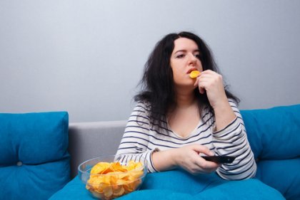 kvinne spiser potetgull i sofaen