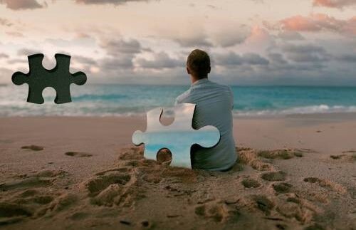 Mann sitter på stranden ved puslespillbrikke