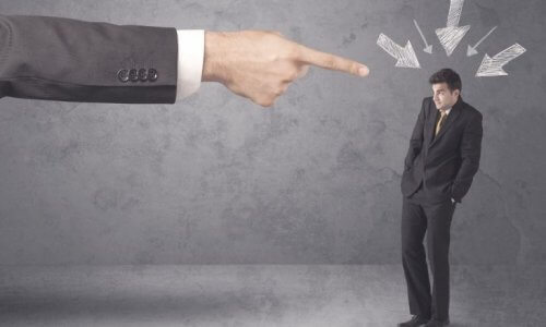 En stor dresskledd arm peker dømmende på en andre, betydelig mindre dresskledd mann.