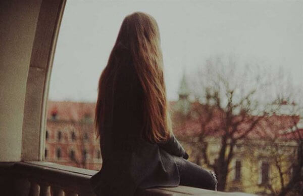 Kvinne sitter på balkongen konfronterer sin ensomhet