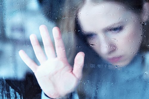 Trist kvinne ser ut av vinduet, konfronterer smerte